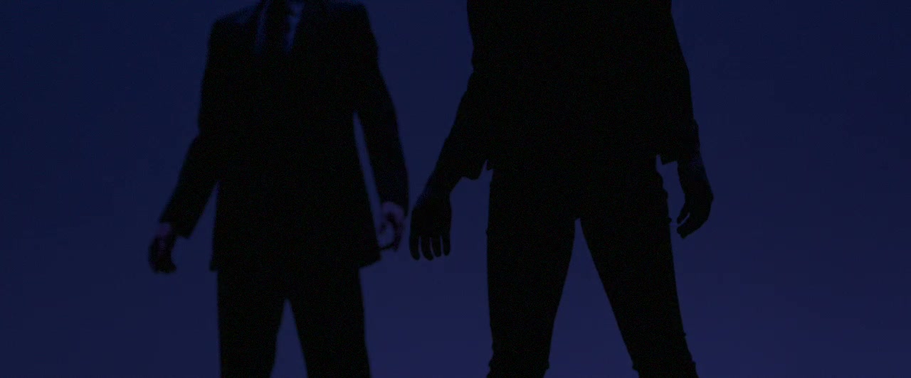 Two dancers in silhouette against a deep indigo backdrop, suits and the suggestion of slow movement at the edge of the frame — a still from the Play promo for Houston Ballet's Nine Sinatra Songs triple bill.
